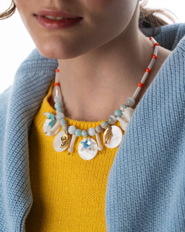 A handcrafted Seashell Serenity Necklace featuring seashells, mother-of-pearl, Swarovski crystals, and gold-plated charms.